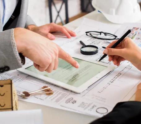 Expertos de organismos certificadores revisando documentación técnica y planos para validar normativas vigentes.